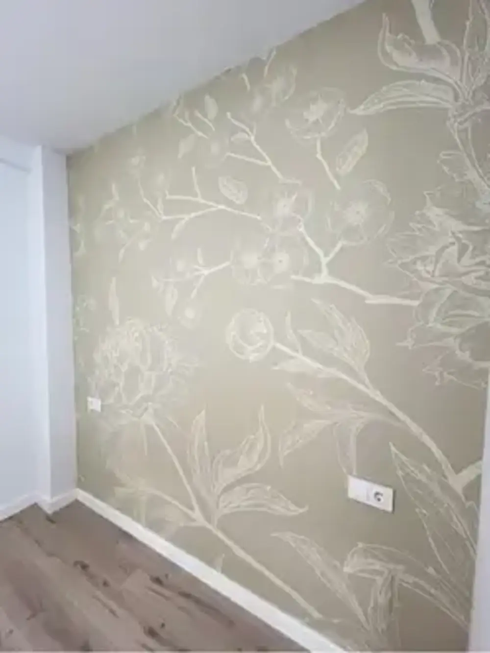 Pintores Cartagena aplicando papel pintado de textura clara en habitación reformada